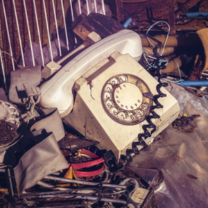 Ein Telefon mit Wählscheibe steht im Müll