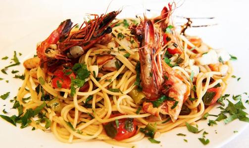 Spaghetti mit Shrimps auf einem Teller mit Soße und Kräutern