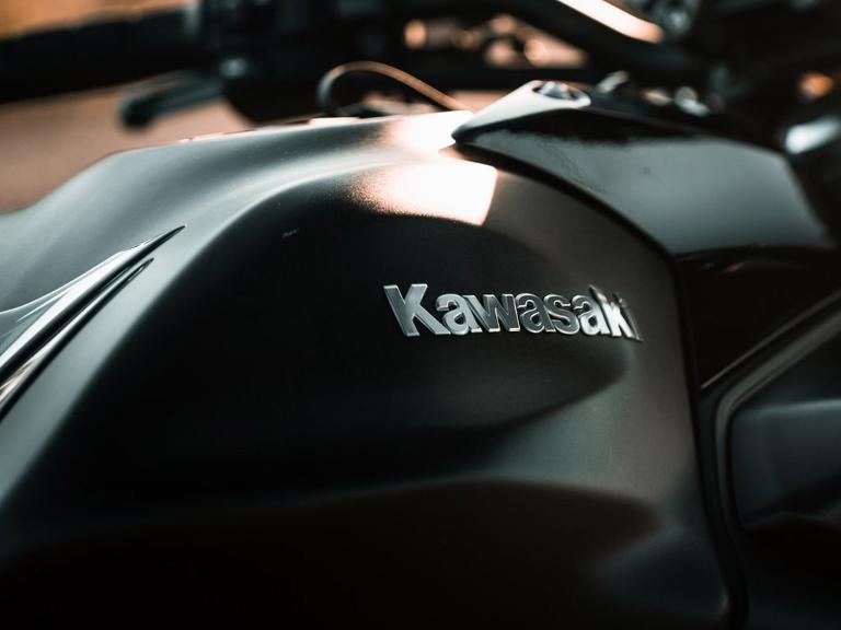 Silberner Kawasaki Schriftzug auf einem schwarzen Motorrad