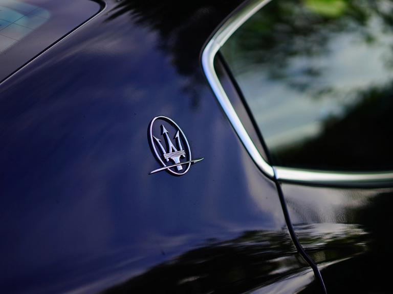 Ein silbernes Zeichen auf einem schwarzen Auto, hinten neben dem Autofenster
