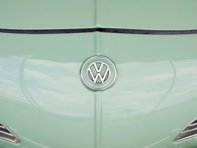 Das VW Zeichen auf der Motorhaube eines mintgrünen Autos