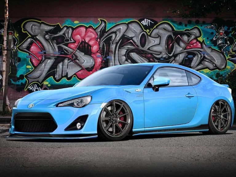 Ein blauer, tiefer gelegter Sportwagen vor einem Graffiti
