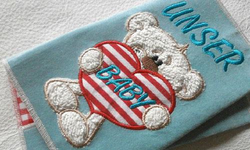 Decke mit einem Teddybären bestickt der ein Herz trägt