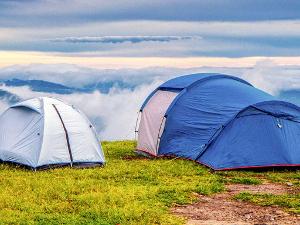 Zwei Zelte auf einer Wiese vor einem Abhang