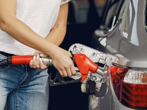 Eine Frau hält den Zapfhahn und befüllt das Auto mit Benzin