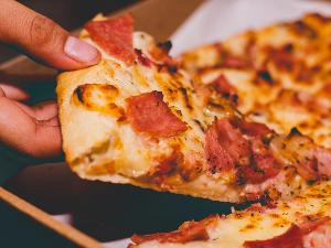 Eine Hand greift nach einem Stück Pizza