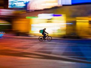 Ein Mensch fährt auf einem Fahrrad, der Hintergrund ist verwischt