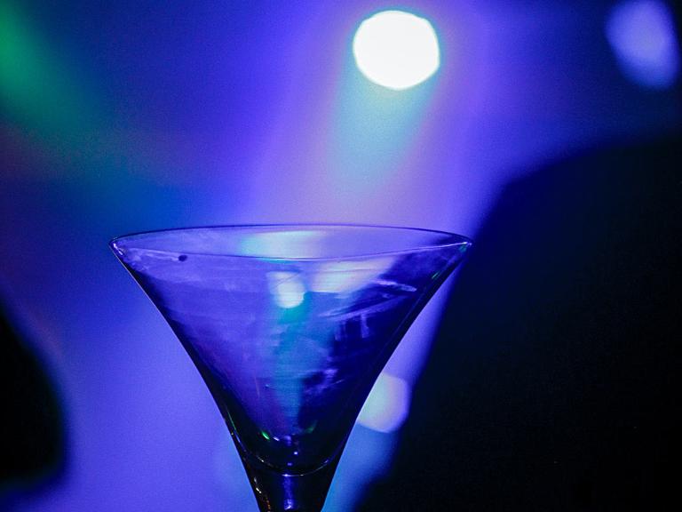 Ein Martiniglas, im Hintergrund bläulich-lilafarbenes Licht