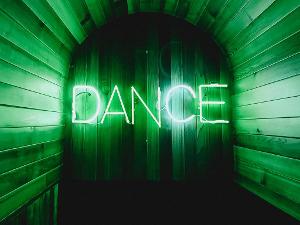 Grüne Lichtschrift- das Wort Dance hängt an der Wand