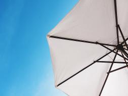 Ein weißer Sonnenschirm unter strahlend blauem Himmel