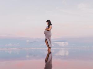 Eine schwangere Frau steht im flachen Wasser