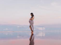 Eine schwangere Frau steht im flachen Wasser