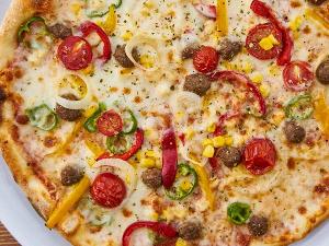 Eine Pizza belegt mit Paprika, Tomaten, Zwiebeln und Hackbällchen