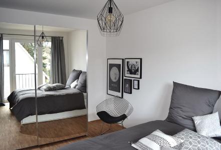 Schlafzimmer mit Spiegelkleiderschrank, Doppelbett und einem Sessel