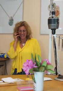 Portraitbild von Martina Lam in gelber Bluse mit Telefon in der Hand.