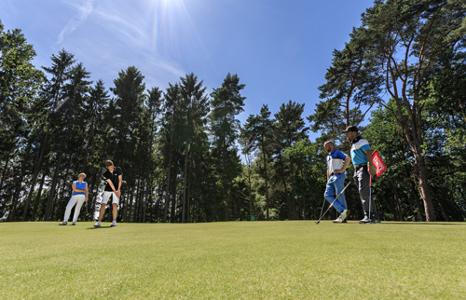Vier Menschen stehen auf der Wiese und spielen Golf