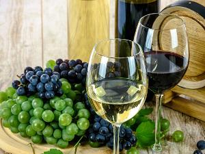 Weintrauben liegen neben zwei Weingläsern auf einem Holzbrett