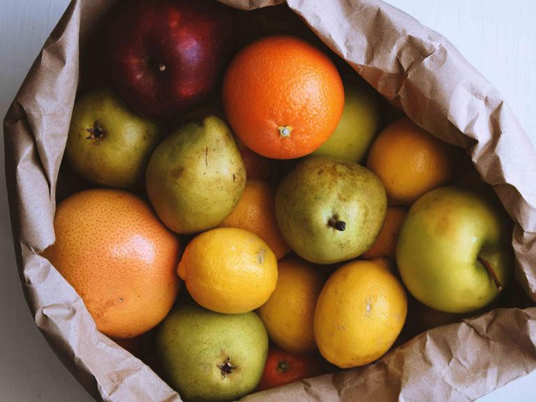 Eine Papiertüte gefüllt mit Äpfeln, Orangen und Zitronen