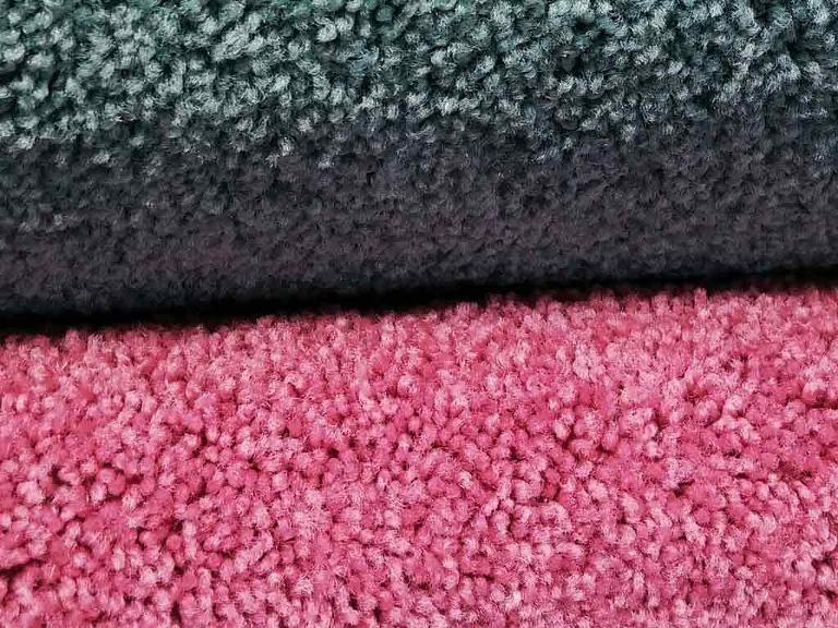 Ein rosa- und ein schwarzfarbener Teppich liegen übereinander