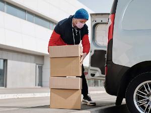 Ein Mensch packt Kartons in einen Lieferwagen