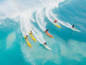 Sechs Menschen stehen auf ihren Surfbrettern und reiten auf einer Welle