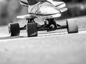 Ein Mensch steht auf einem Skateboard- Nahaufnahme der Schuhe auf dem Board, schwarz-weiß Aufnahme