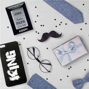 Eine Handyhülle, ein Feuerzeug, eine Brille, eine Krawatte und ein eingepacktes Geschenk mit Schleife