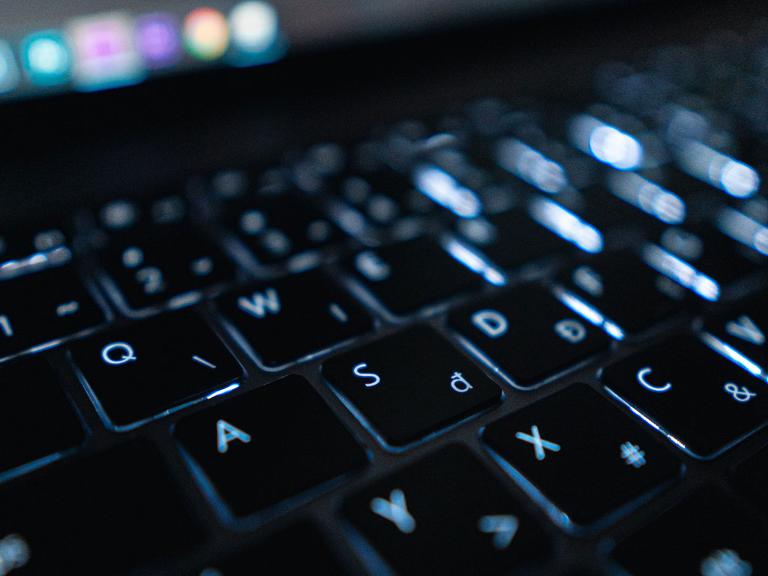 Schwarze Laptop-Tastatur mit Bildschirm im Hintergrund