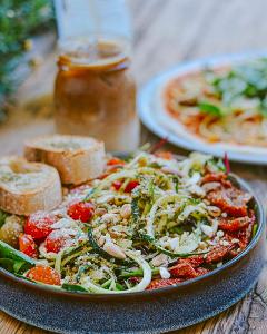 Zucchini in Streifen mit Tomaten und Baguette auf einem Teller