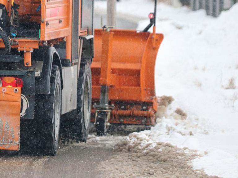 Oranger Schneepflug räumt die Straße von Schnee frei