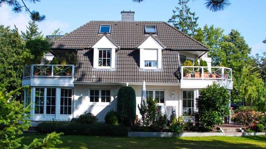 Freistehendes, weißes Haus mit grauem Dach und Garten