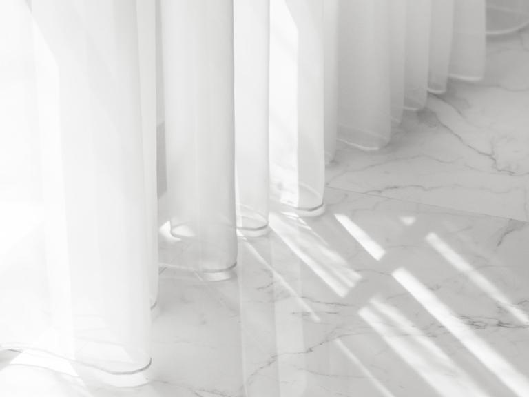 Weiße Lichtdurchlässige Gardinenschals und ein weißer Marmorboden
