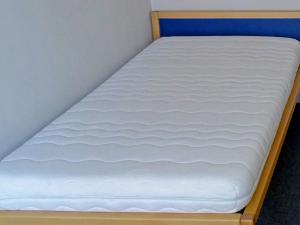 Eine Matratze eingelassen in ein Bettgestell aus hellem Holz und einem blauen Kopfteil