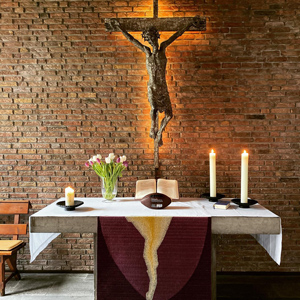Ein Altar mit Kerzen, Blumen und im Hintergrund ein Kreuz mit indirekter Beleuchtung