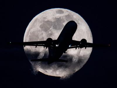 Ein Flugzeug vor dem Mond und dem dunklen Nachthimmel
