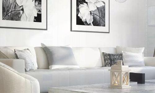 Blick in ein Wohnzimmer mit weißem Sofa und schwarzweiß Bildern an der Wand