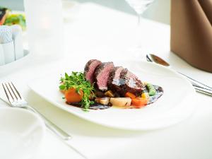 Geschnittenes Steak, Gemüse und Soße auf einem weißen Teller