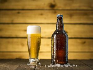 Biergals und Bierflasche vor hölzernem Hintergrund