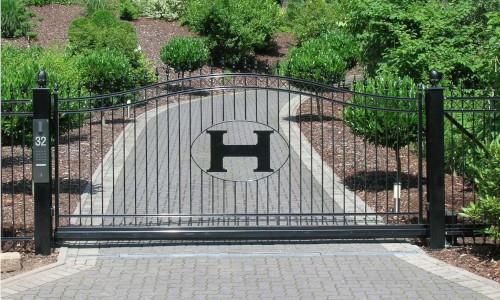 Edel aussehender Zaun mit eingelassenem H vor einer Auffahrt