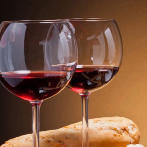 Zwei Weingläser, gefüllt mit Rotwein und einem Baguette