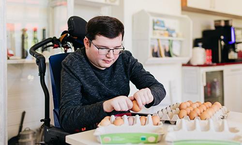 Ein Junge im Rollstuhl packt Eier in Kartons