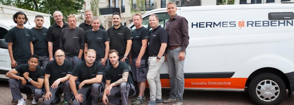 14 Menschen stehen vor einem Transporter der Firma HERMES + REBEHN MSR & Elektrotechnik GmbH und lächeln in die Kamera