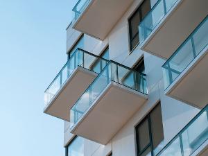 Balkone aus Glas mit einem schwarzen Geländer, an einer hellen Hauswand
