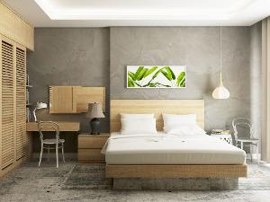 Ein Zimmer mit einem Bett, einem Schrank und einem kleinen Tisch aus hellem Holz, die Wand ist hellgrau gestrichen und die Decke weiß