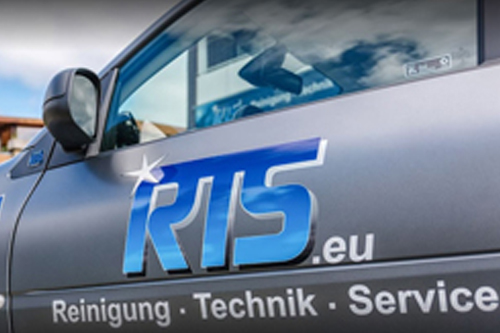 Ein silbernes Auto mit RTS Logo Aufdruck auf der Tür der Fahrerseite