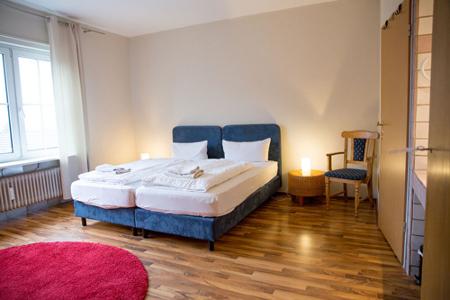 Blaue Betten stehen nebeneinander auf einem Holzfußboden und weißen Wänden