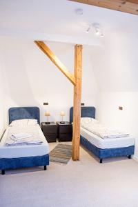 Zwei blaue Einzelbetten stehen neben Nachtschränken, vor einer weißen Wand und Holzbalken