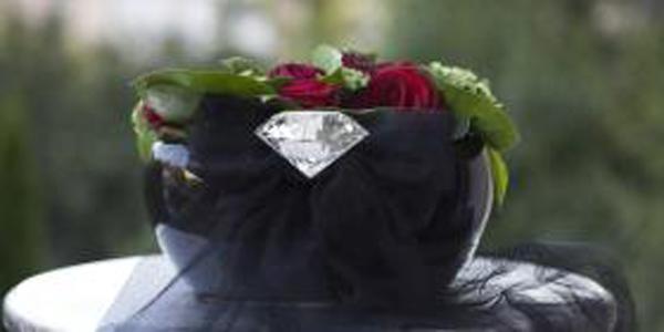 Ein schwarzer Topf mit roten und grünen Blumen darin und einem Diamanten daran