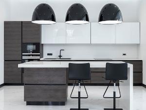 Weiße lackierte Küche mit Tresen, davor zwei Stühle und darüber hängen drei schwarze lampen