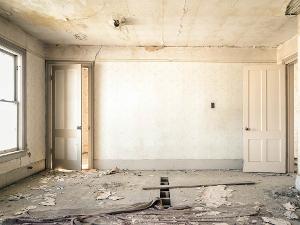 Ein leerer Raum mit abgerissenen Tapeten und einem kaputten Fußboden